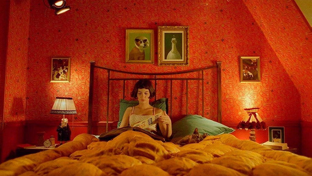 Amélie Poulain, assise dans son lit qui feuillette un album photo.